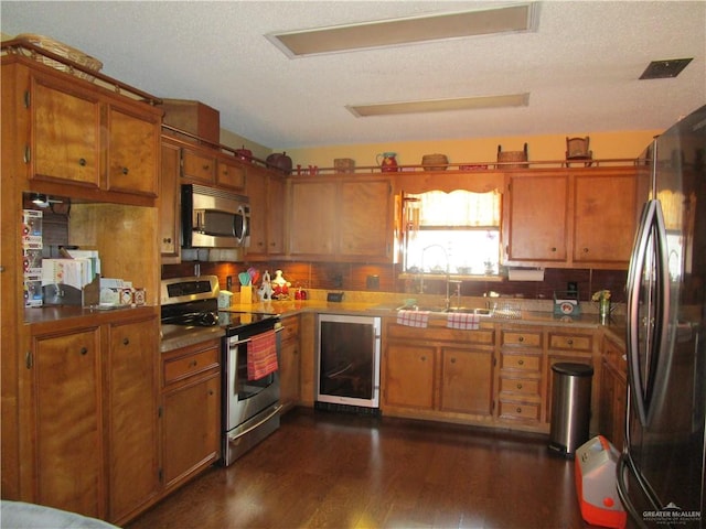 kitchen featuring sink, a textured ceiling, dark hardwood / wood-style flooring, stainless steel appliances, and beverage cooler