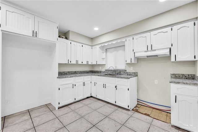 kitchen featuring light tile patterned floors, dark stone countertops, white cabinets, and sink