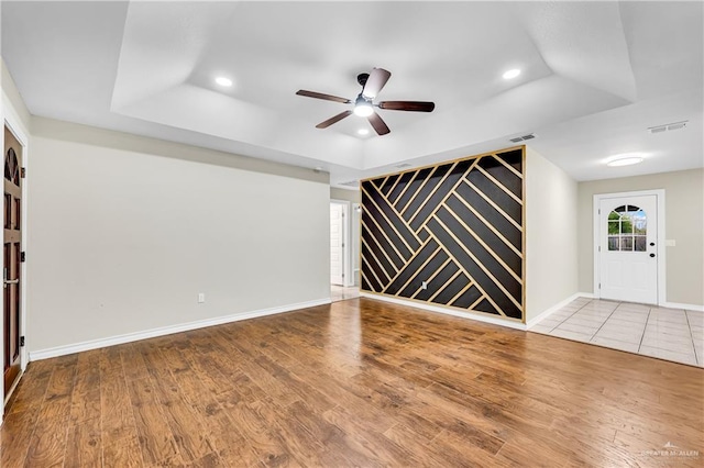 interior space with a raised ceiling, wood-type flooring, and ceiling fan