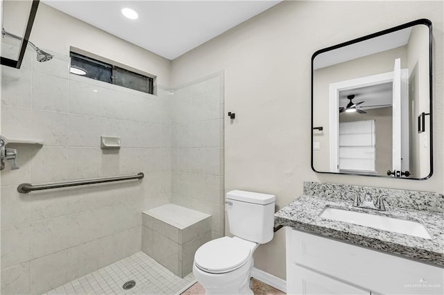 bathroom featuring ceiling fan, toilet, vanity, and tiled shower