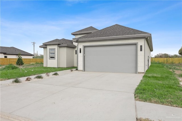 prairie-style house featuring a garage, a shingled roof, fence, concrete driveway, and stucco siding