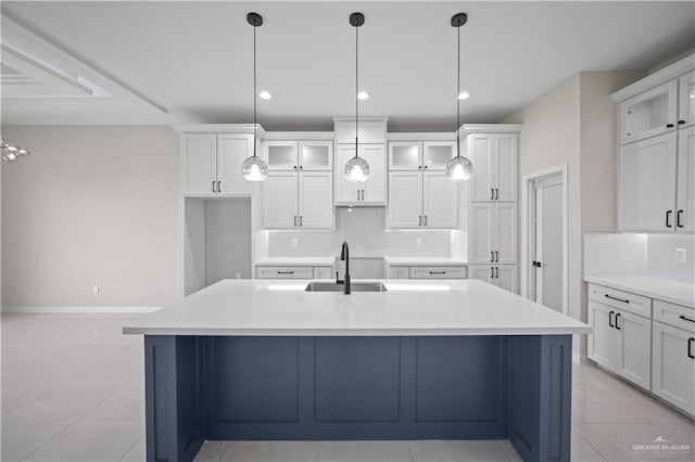 kitchen with a kitchen island with sink, white cabinetry, decorative backsplash, and a sink