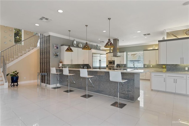kitchen featuring island exhaust hood, decorative backsplash, built in appliances, and ornamental molding
