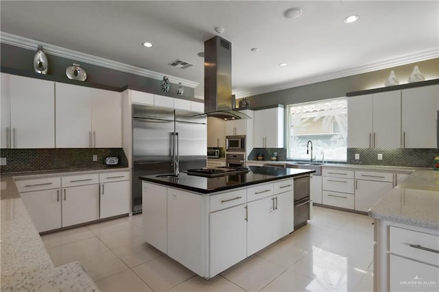kitchen with backsplash, visible vents, crown molding, island range hood, and built in appliances