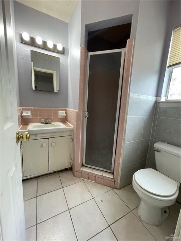 full bath with tile walls, a stall shower, wainscoting, vanity, and tile patterned floors