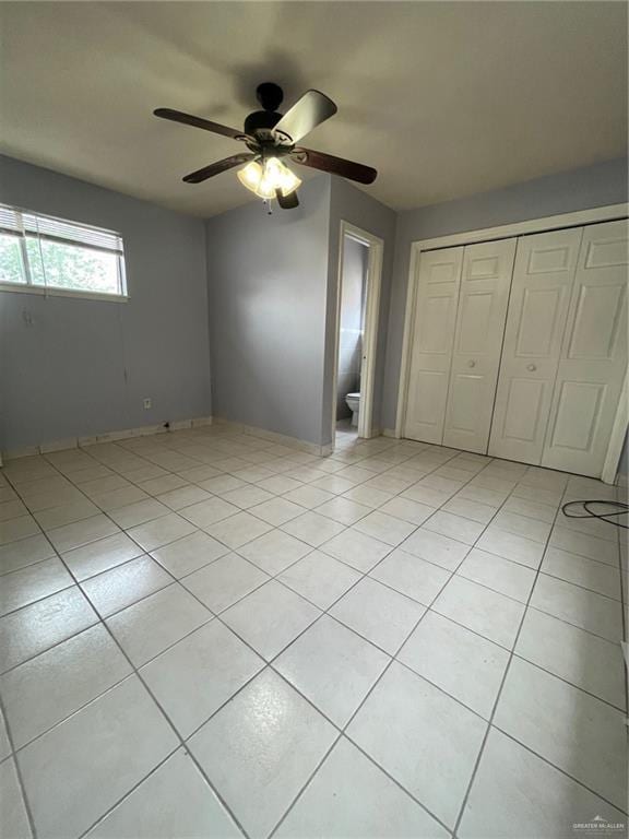 unfurnished bedroom with light tile patterned floors, a closet, and a ceiling fan