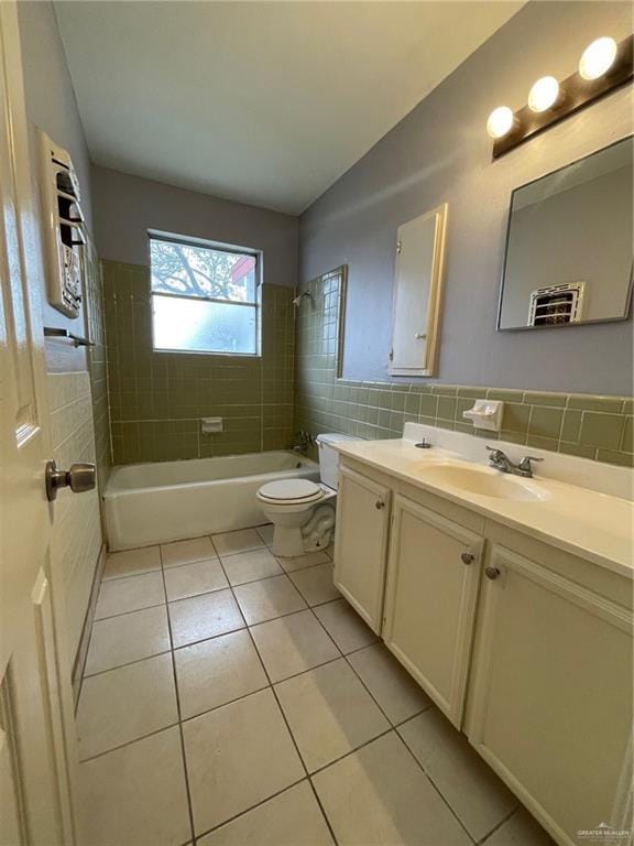 bathroom featuring toilet, tile patterned floors, vanity, shower / washtub combination, and tile walls