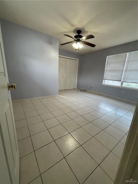 unfurnished bedroom featuring baseboards, a ceiling fan, a closet, and tile patterned floors