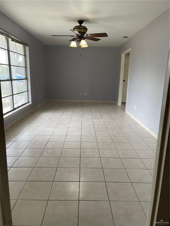 empty room featuring light tile patterned flooring, ceiling fan, and baseboards