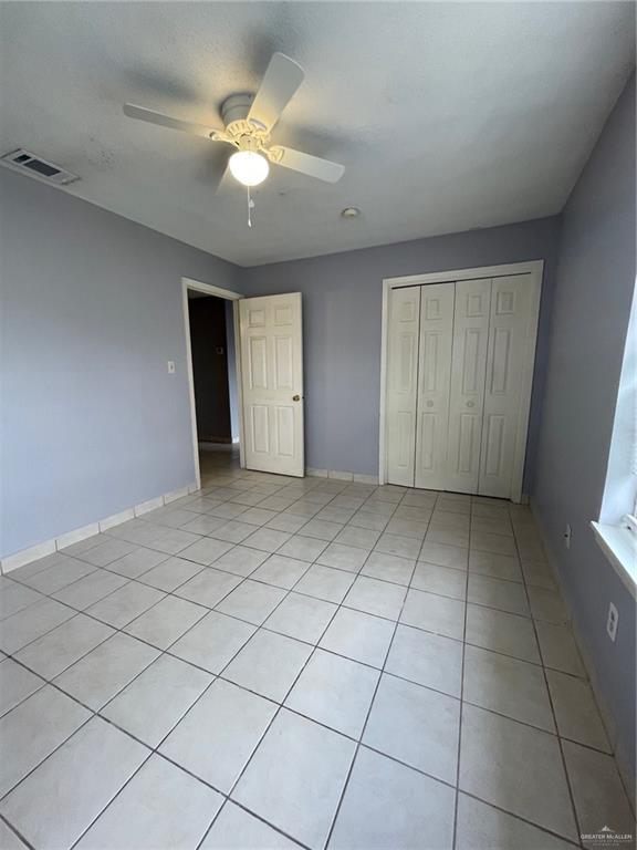 unfurnished bedroom featuring a closet, visible vents, baseboards, and light tile patterned flooring