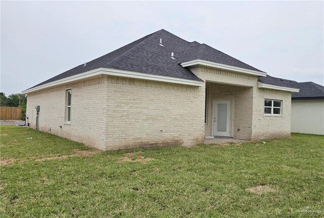 406 Zapata St, San Juan, TX 78589 - back of property featuring brick siding, a yard, and a shingled roof