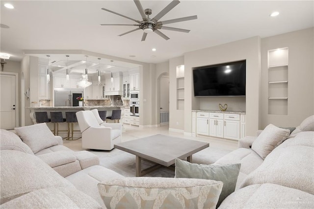 living room featuring built in shelves and ceiling fan