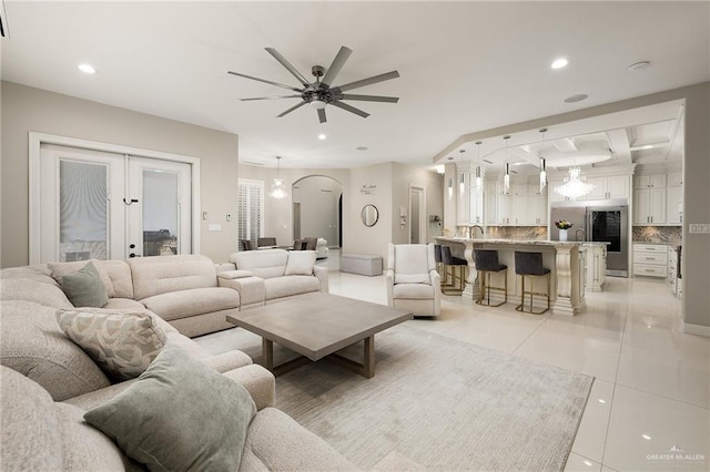 tiled living room featuring french doors, ceiling fan, and sink