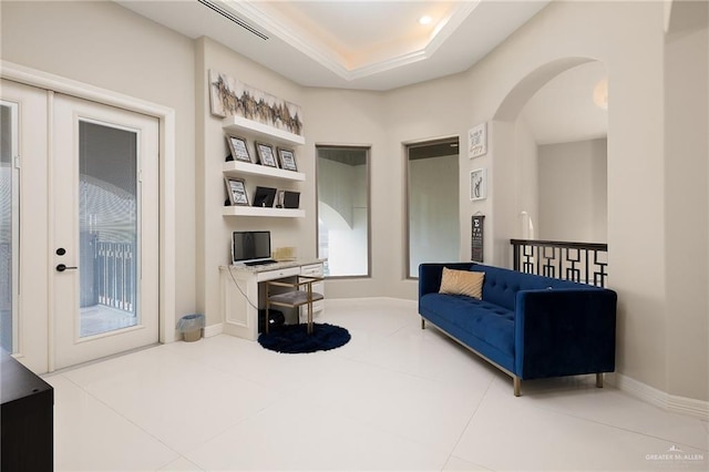 sitting room with a tray ceiling and tile patterned floors