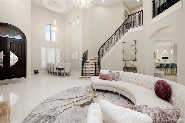 living room with light tile patterned flooring, a towering ceiling, and an inviting chandelier