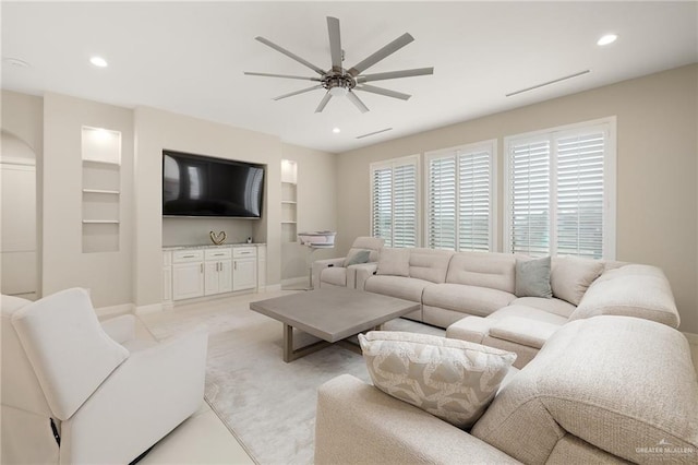 living room with light colored carpet, built in features, and ceiling fan