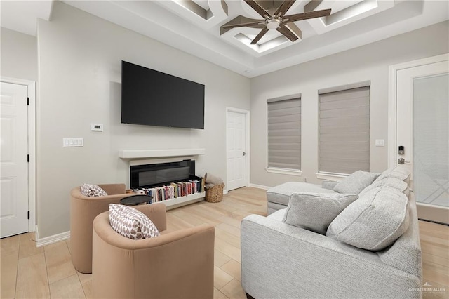 living room with coffered ceiling, ceiling fan, and light hardwood / wood-style flooring