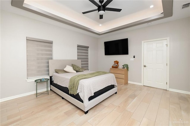 bedroom featuring ceiling fan, a tray ceiling, and light hardwood / wood-style floors