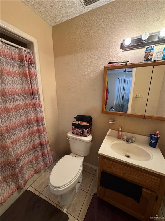 411 N Fir St, Pharr, TX 78577 - full bath featuring vanity, tile patterned floors, a textured ceiling, and a shower with shower curtain