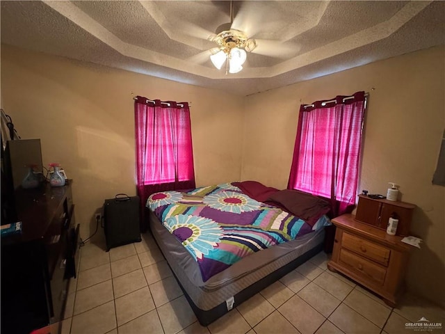 411 N Fir St, Pharr, TX 78577 - bedroom with light tile patterned flooring, a tray ceiling, a textured ceiling, and a ceiling fan
