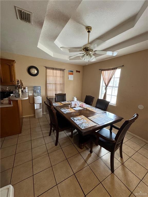 411 N Fir St, Pharr, TX 78577 - dining area with a tray ceiling, a textured ceiling, light tile patterned floors, and ceiling fan