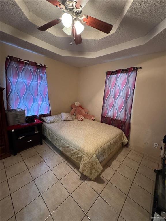 411 N Fir St, Pharr, TX 78577 - bedroom featuring a tray ceiling, light tile patterned floors, a textured ceiling, and a ceiling fan