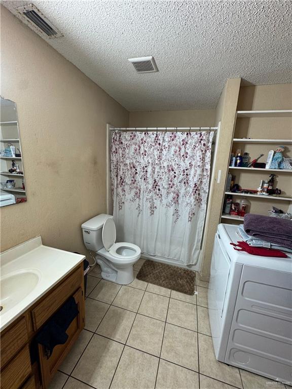 411 N Fir St, Pharr, TX 78577 - full bath with washer and dryer, a textured ceiling, vanity, tile patterned floors, and a shower with curtain