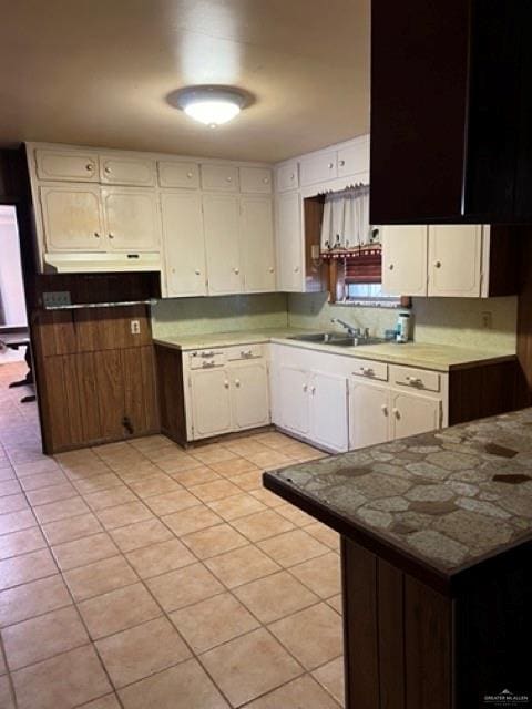 kitchen with white cabinetry, sink, and light tile patterned floors