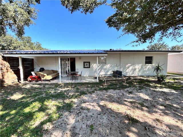 rear view of house with outdoor lounge area, cooling unit, and a patio