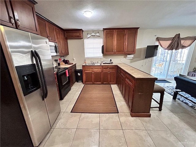 kitchen with a healthy amount of sunlight, light tile patterned floors, and stainless steel appliances