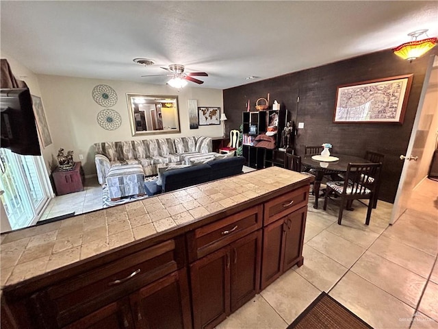 kitchen featuring tile countertops, ceiling fan, dark brown cabinetry, and light tile patterned floors