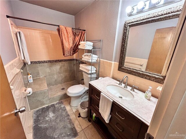 bathroom featuring walk in shower, tile patterned floors, toilet, vanity, and tile walls