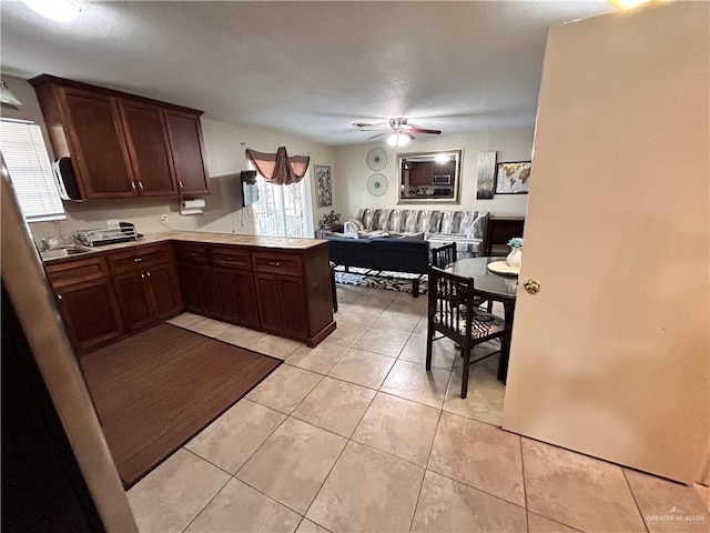 kitchen with kitchen peninsula, sink, ceiling fan, light tile patterned floors, and dark brown cabinetry