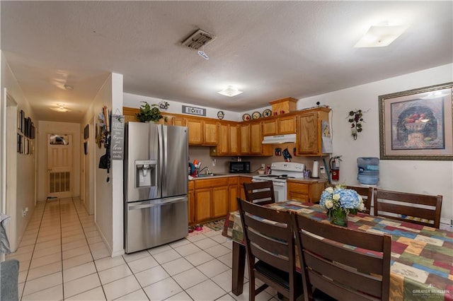 kitchen featuring light tile patterned flooring, stainless steel fridge, white range oven, and sink