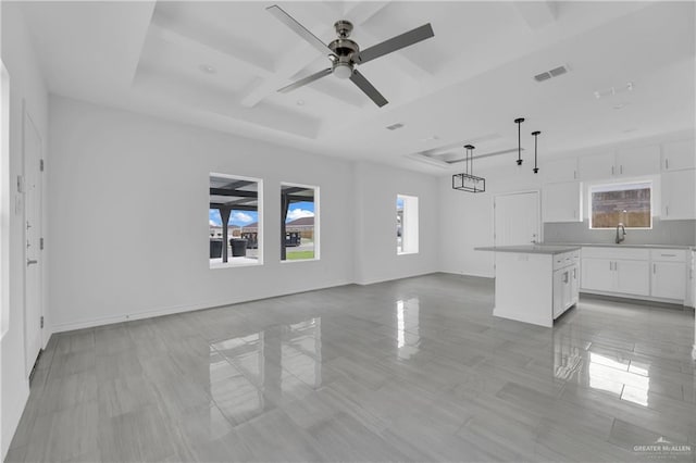 unfurnished living room featuring a tray ceiling, ceiling fan, and sink