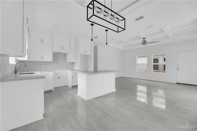 kitchen featuring white cabinets, sink, ceiling fan, beamed ceiling, and a kitchen island