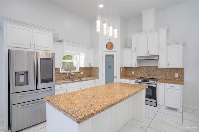 kitchen featuring a center island, sink, a high ceiling, appliances with stainless steel finishes, and white cabinets