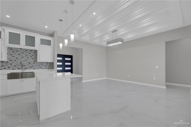 kitchen featuring a kitchen island, pendant lighting, tasteful backsplash, white cabinetry, and sink