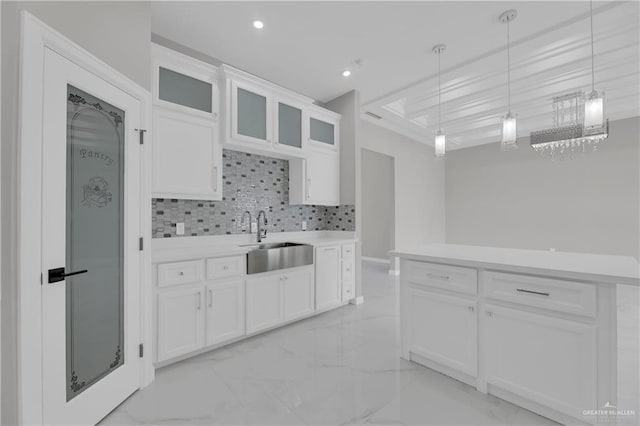 kitchen with sink, white cabinetry, backsplash, hanging light fixtures, and a center island