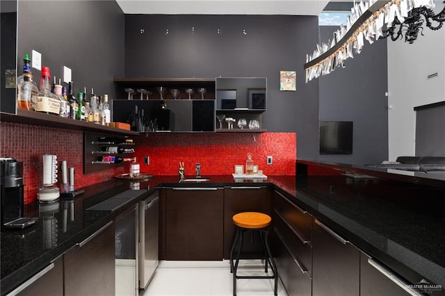 bar featuring dark stone countertops, decorative backsplash, and dishwasher