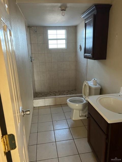 bathroom featuring vanity, tile patterned floors, toilet, and a tile shower