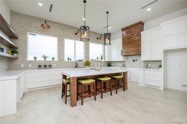 kitchen featuring white cabinets, a kitchen island, sink, and tasteful backsplash