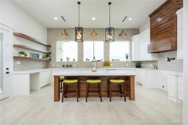 kitchen featuring a breakfast bar, decorative backsplash, a center island, and white cabinetry