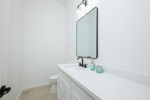 bathroom with hardwood / wood-style flooring, vanity, and toilet