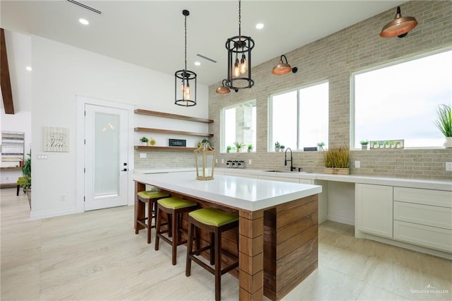 kitchen with a center island, sink, tasteful backsplash, pendant lighting, and a kitchen bar