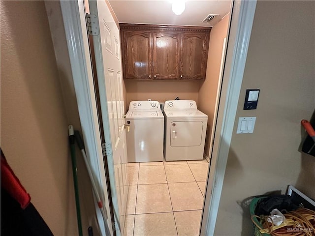 clothes washing area with cabinets, light tile patterned floors, and separate washer and dryer