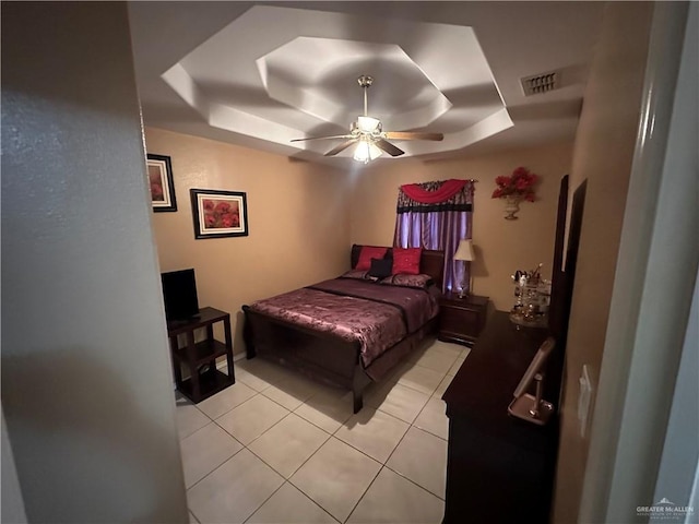 bedroom featuring a raised ceiling, ceiling fan, and light tile patterned floors