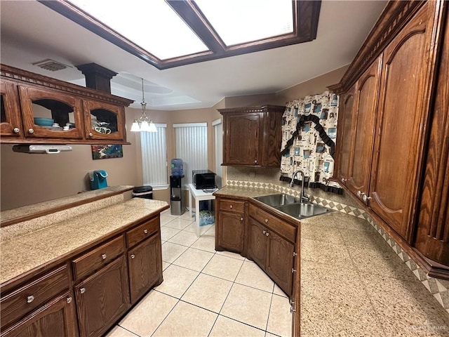 kitchen with decorative backsplash, sink, light tile patterned floors, a notable chandelier, and hanging light fixtures