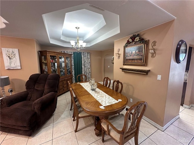 dining room with a tray ceiling, an inviting chandelier, and light tile patterned flooring