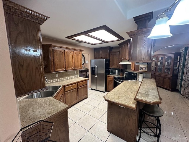 kitchen with pendant lighting, black appliances, sink, decorative backsplash, and light tile patterned floors